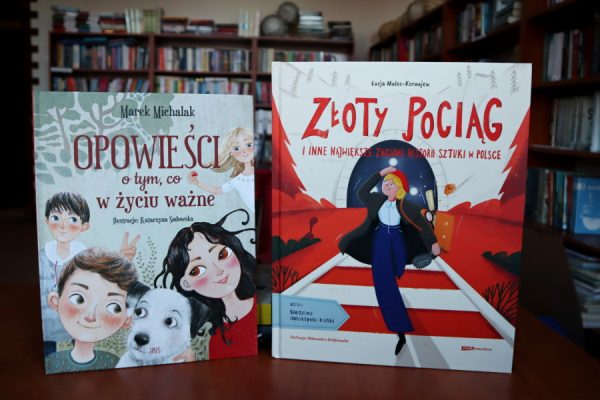 książki leżące ba biurku w tle regały biblioteczne