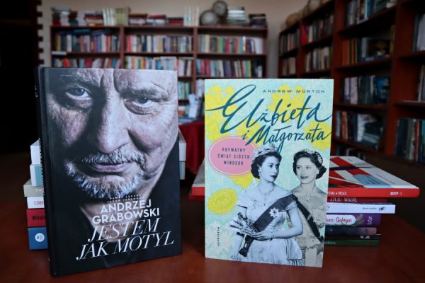 książki leżące ba biurku w tle regały biblioteczne