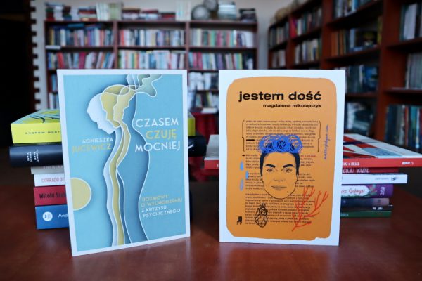 książki leżące ba biurku w tle regały biblioteczne