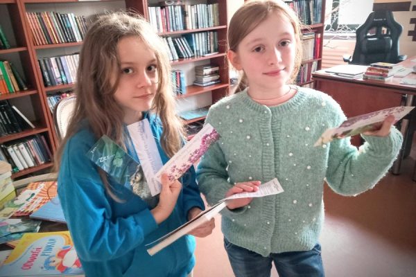 dwie dziewczynki za nimi regały z ksiażkami