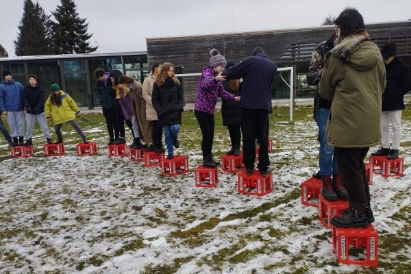 grupa młodzieży w trakcie zabawy, stoją na czerwonych skrzynkach
