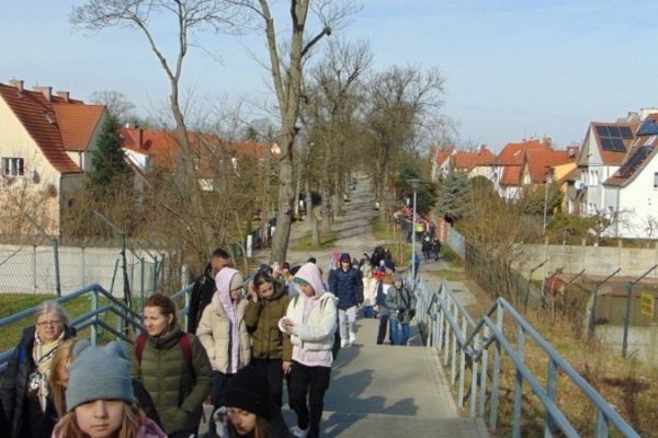 grupa turystów, w tle domy, droga i wejście na schody