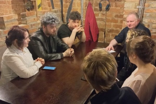 grupa młodych ludzi siedzi przy stole