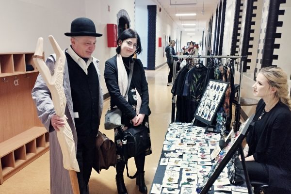 mężczyzna w meloniku z kosturem ogląda stoisko z biżuterią