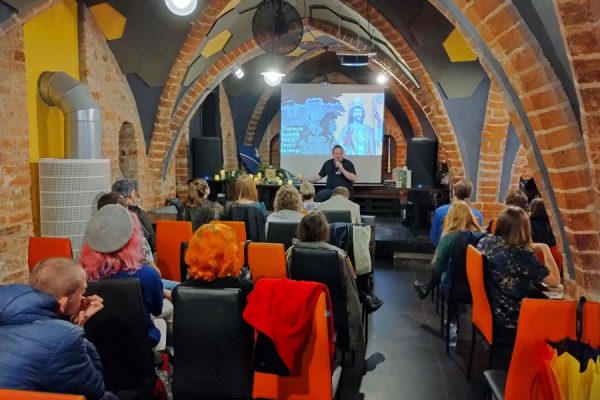 publiczność zgromadzona na wydarzeniu, na scenie osoba recytuje