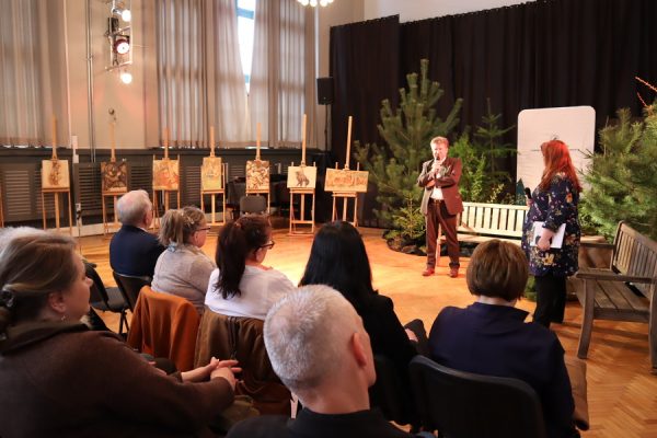 publiczność w trakcie wydarzenia w tle dwie osoby na scenie