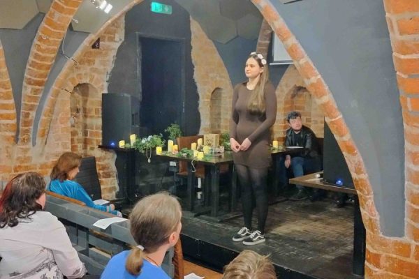 publiczność zgromadzona na wydarzeniu, na scenie osoba występująca