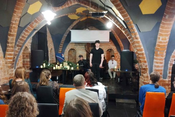 publiczność zgromadzona na wydarzeniu, na scenie osoba występująca