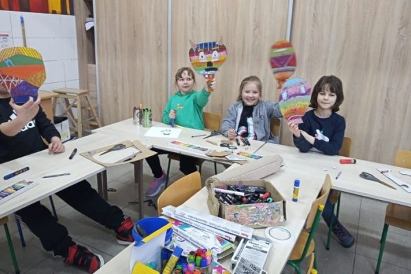 uczestnicy pracowni plastycznej z maskami w dłonaich