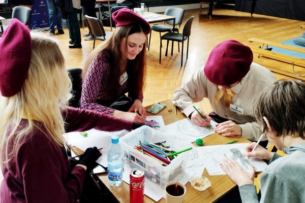 młodzi ludzie siedzą przy stole i rysują