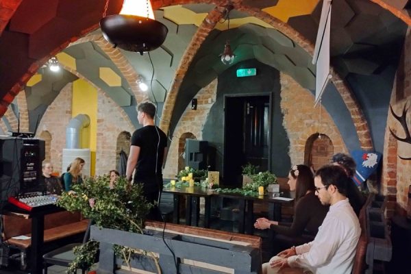 publiczność zgromadzona na wydarzeniu, na scenie osoba występująca