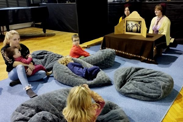 dzieci leżą na poduchach przed nimi teatrzyk