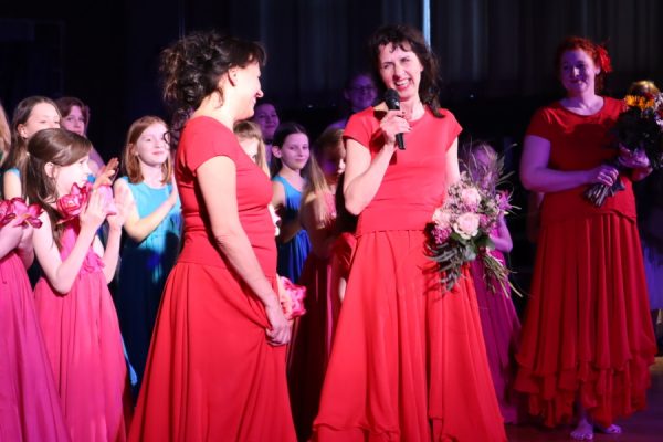 dwie kobiety jedna ma mikrofon w tle dziewczęta