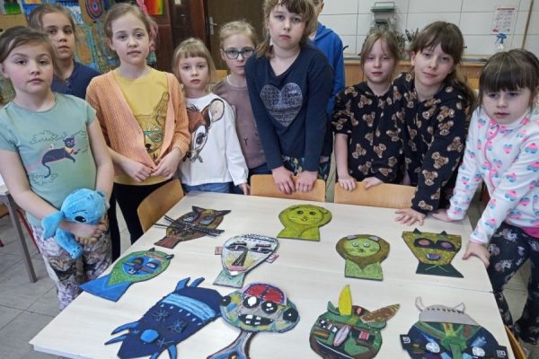 uczestnicy pracowni plastycznej pozują do zdjęcia ze swoimi pracami