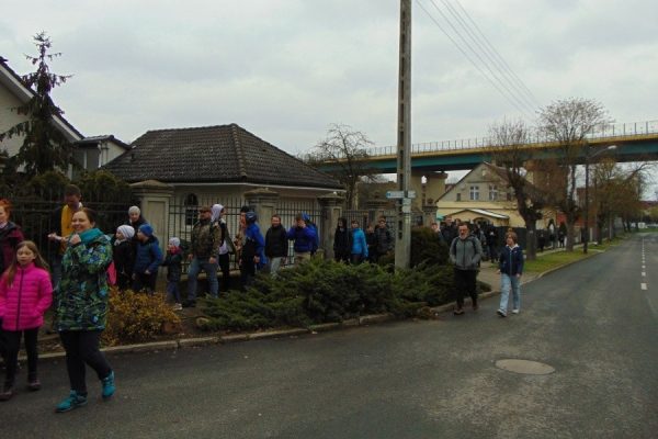 grupa młodzieży idzie chodnikiem, domy, w tle wiadukt autostrady