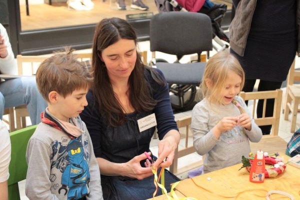 dwoje dzieci z nauczycielką tworzy ozdoby świateczne