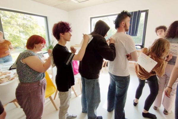 grupa młodzieży pisze coś na kartkach