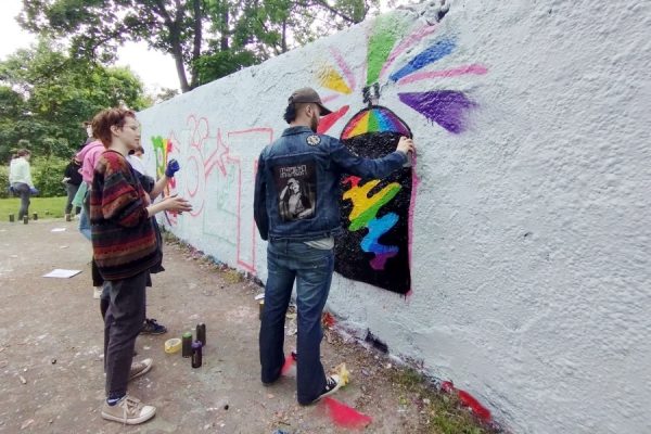 dwoje młodych ludzi maluje coś na murze