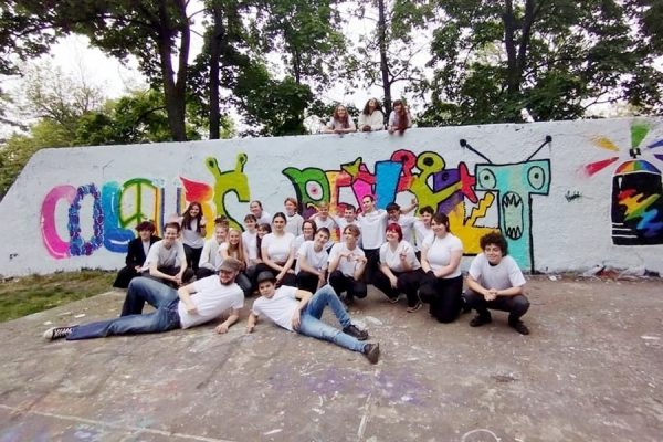 grupa młodzieży na tle muralu z graffiti