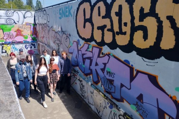 grupa młodzieży na tle muralu z graffiti