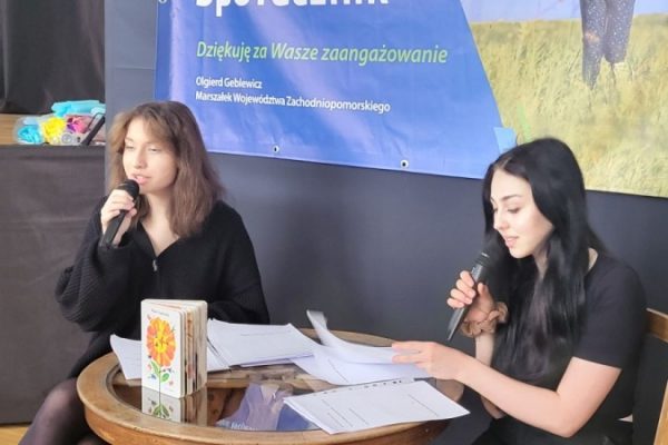 dwie dziewczyny czytają tekst siedząc przy stoliku