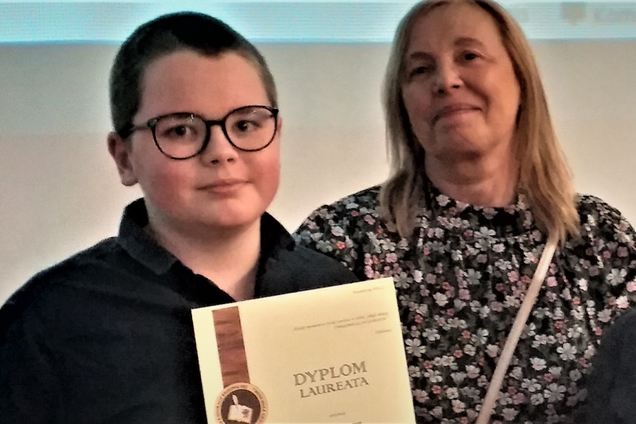 chłopiec z dyplomem obok stoi kobieta