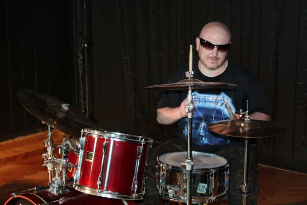 mężczyzna w ciemnych okularach gra na perkusji