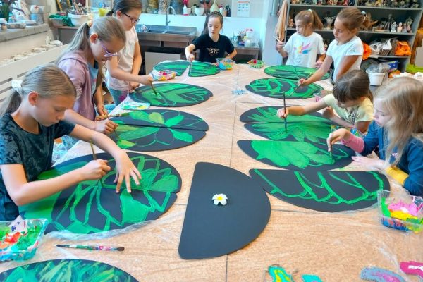 dzieci w trakcie warsztatów siedzą przy stole tworząc prace