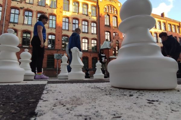 uczestnicy zajęć grają w szachy na boisku