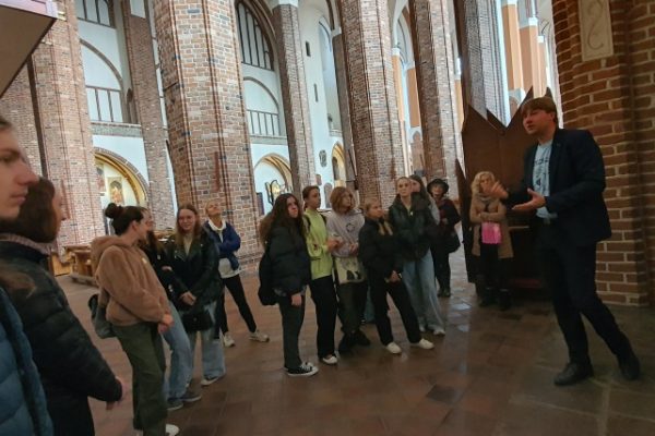 grupa młodzieży z przewodnikiem zwiedza katedrę