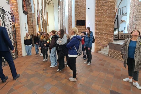 grupa młodzieży z przewodnikiem zwiedza katedrę