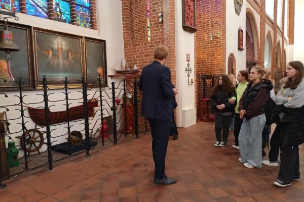 grupa młodzieży z przewodnikiem zwiedza katedrę