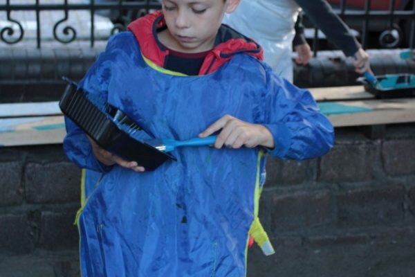 chłopiec w trakcie malowania ławki