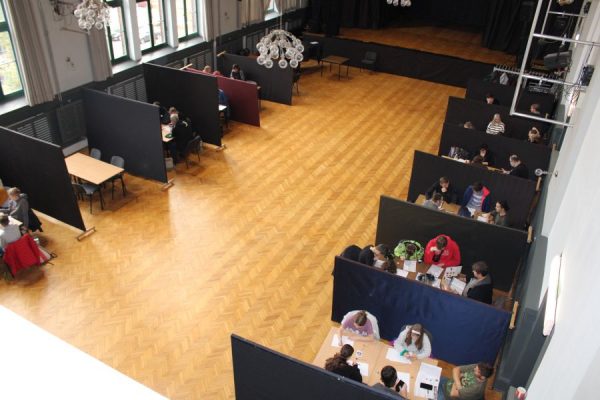 stoliki ustawione w aulu oddzielone parawanami