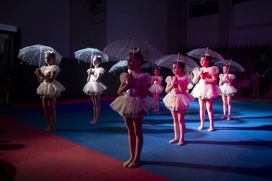 grupa dziewczynek na macie trzymają parasolki