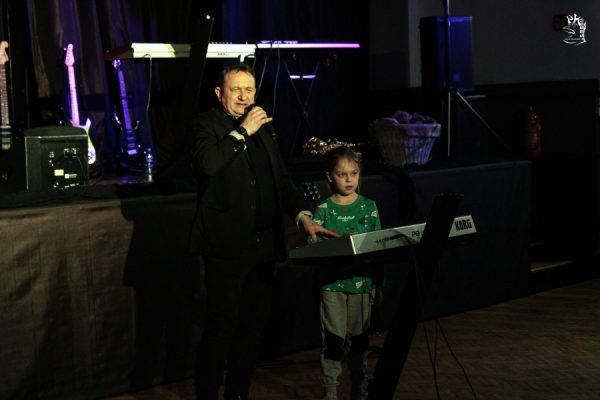 mężczyzna z mikrofonem i dziewczynka gra na keboardzie