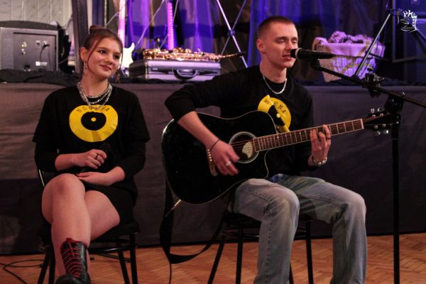 chłopak z gitarą obok siedzi dziewczyna