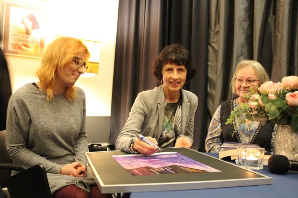 trzy kobiety siedzą przy stole podczas spotkania literackiego