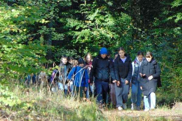 grupa młodzieży idąca przez las