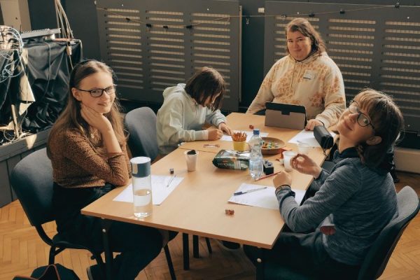 grupa młodzieży podczas gry siedzi przy stole