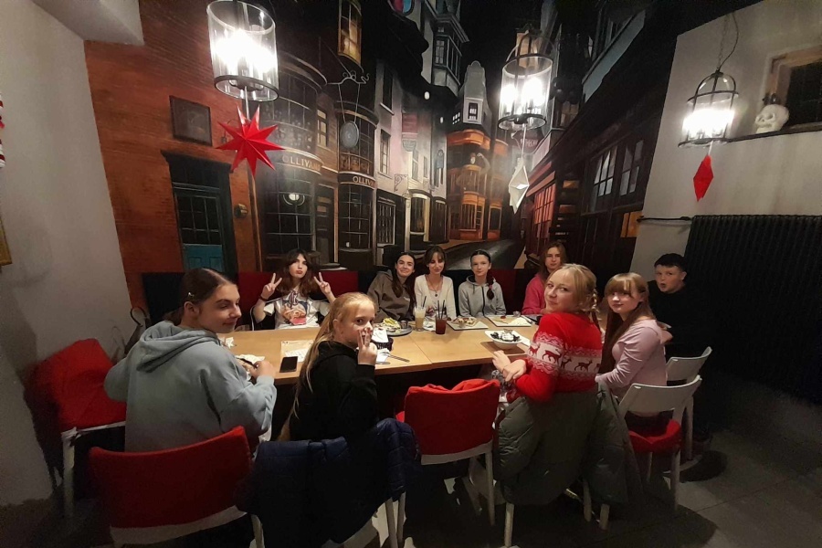 grupa młodzieży siedzi przy stole