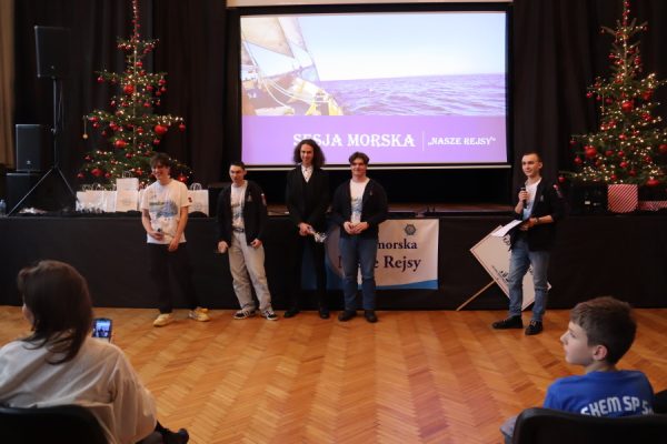 grupa uczestników stoi przed ekranem za nimi napis naszej Rejsy