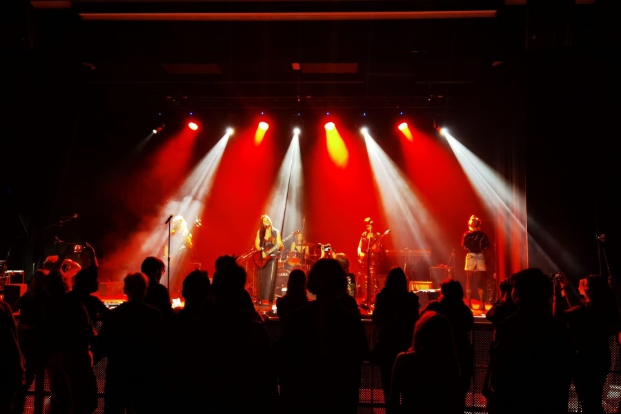 scena pełna świateł a na niej zespół na pierwszym planie publicznosc