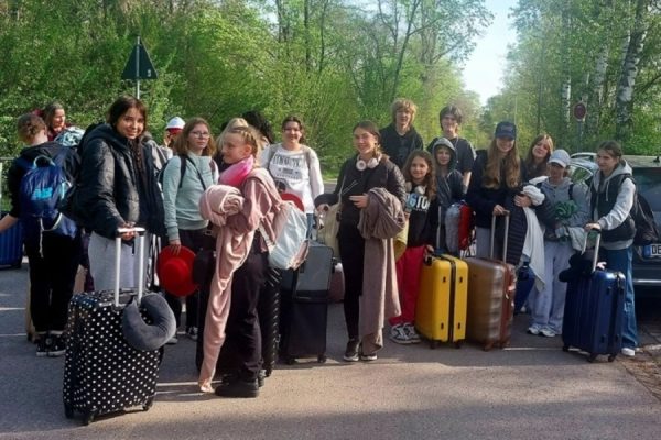 grupa młodzieży z walizkami pozuje do zdjęcia