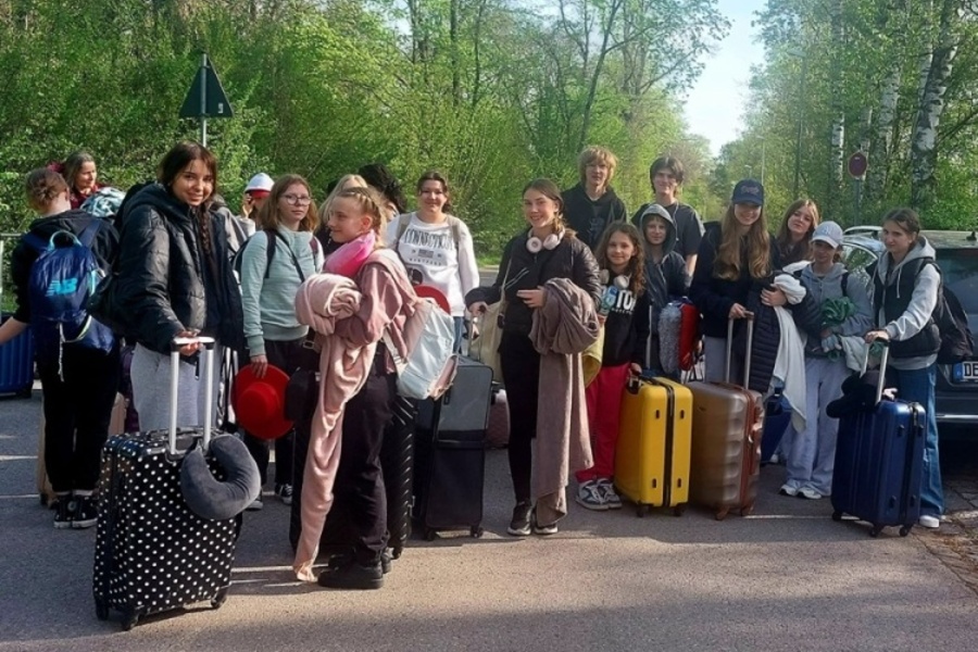 grupa młodzieży z walizkami pozuje do zdjęcia