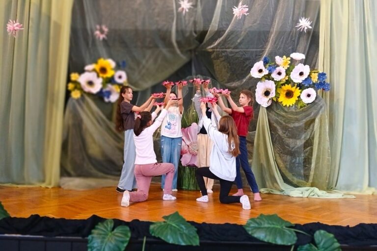 grupa dziewcząt na scenie wśród scenografii kwiatowej