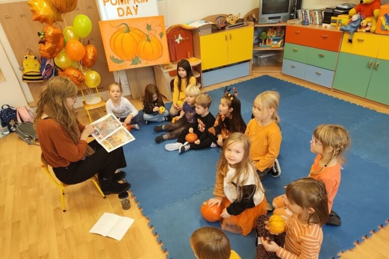 grupa dzieci z nauczycielką czytającą im ksiażkę