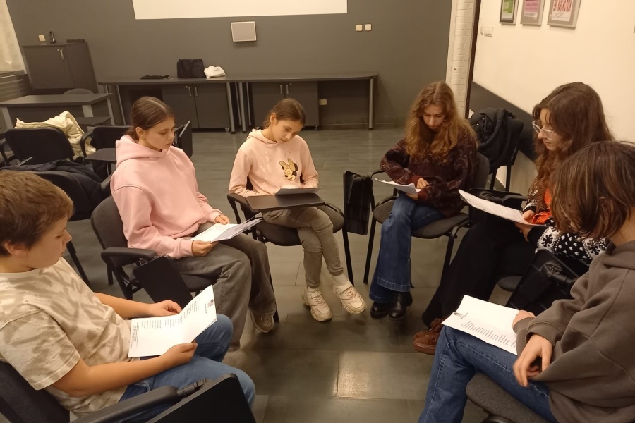 grupa uczestników siedzi z kartkami w ręku