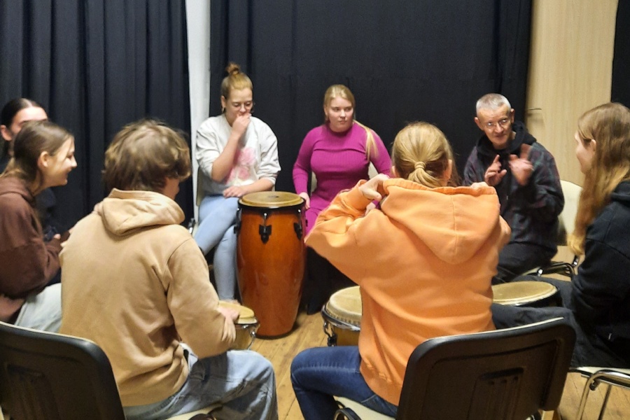 nauczyciel i grupa uczestników przy bębnach